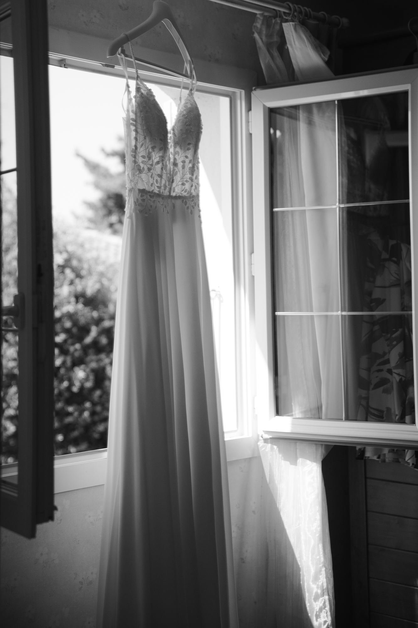 Robe de mariée suspendue près d'une fenêtre
