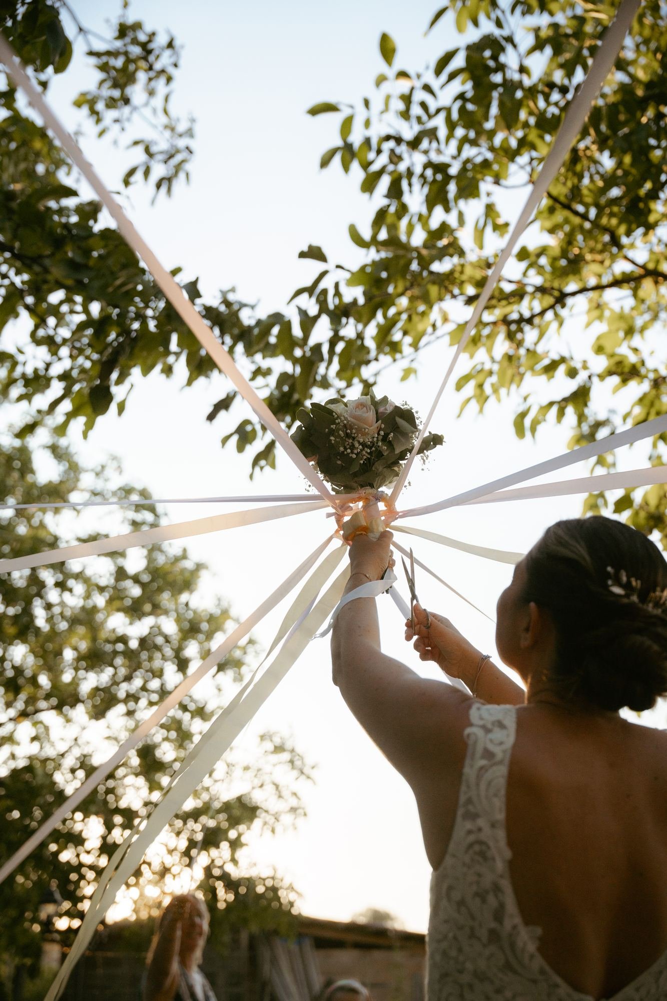 La mariée nouant les rubans du bouquet