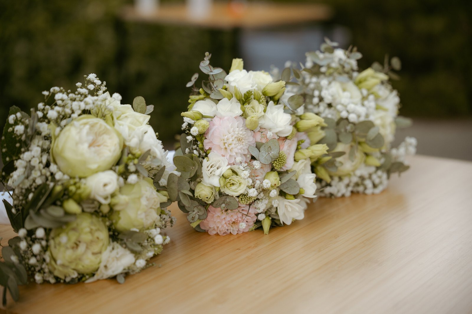 Trois bouquets de mariage posés sur une table en bois